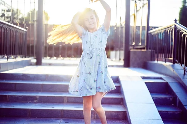 Portret van een mooi meisje, in een modieuze jurk, recht haar haar op een zonnige zomerdag, buiten. Klein meisje met lang haar. Schoonheid en mode baby met gezond haar — Stockfoto