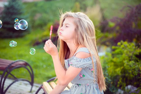 Een tienermeisje op een bankje dat bubbels blaast. Actieve levensstijl kind — Stockfoto