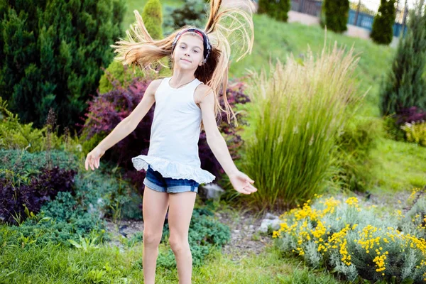 一个漂亮的小女孩的肖像，快乐的孩子，跳在一个绿色的公园里。儿童的积极生活方式 — 图库照片