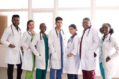 team of young doctors, mixed race. People of different sex, in white coats, with phonendoscopes, posing, smiling