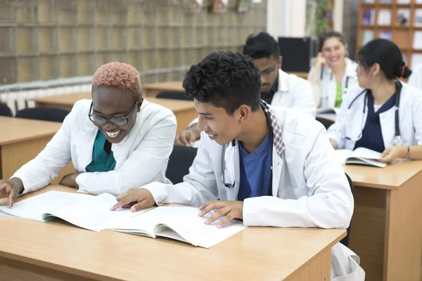 En grupp unga multinationella raser, läkarstudenter. De skriver provet när de sitter vid bordet.. — Stockfoto