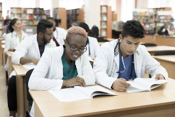Gruppo multinazionale di giovani scienziati medici. Seduto alle loro scrivanie, studiando letteratura medica — Foto Stock