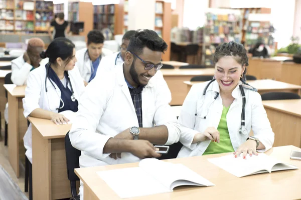 Young mixed race, medical students. Sit at the desk, study medical literature, take an exam, smile — 스톡 사진