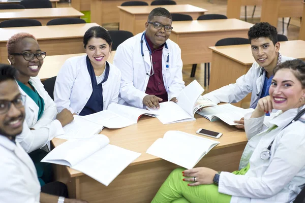 Un gruppo di medici misti. Giovani sorridenti seduti a un tavolo in uno studio ospedaliero che discutono di argomenti medici . — Foto Stock