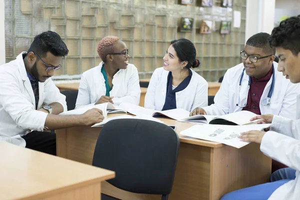 Un gruppo di giovani dottori, razza mista. Sedetevi al tavolo a discutere di argomenti medici . — Foto Stock