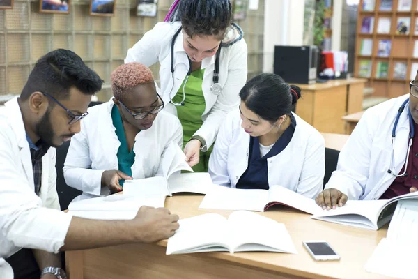 Giovani medici Un gruppo di persone di razza mista, seduti a tavola, a parlare, a discutere di problemi di salute . — Foto Stock