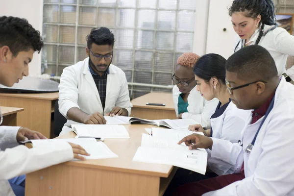 Läkare En grupp unga blandras läkare, sitter vid ett skrivbord på ett kontor, diskuterar medicinska frågor och ämnen. Medicinskt övervägande — Stockfoto