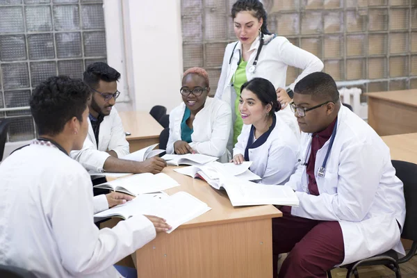 Consejo médico. Un grupo de jóvenes de raza mixta, sentados en una mesa en una oficina del hospital, discute temas médicos . —  Fotos de Stock