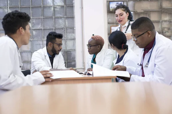 Medical advice. A group of mixed-race young men, sitting at a table in a hospital office, discusses medical topics. — 스톡 사진