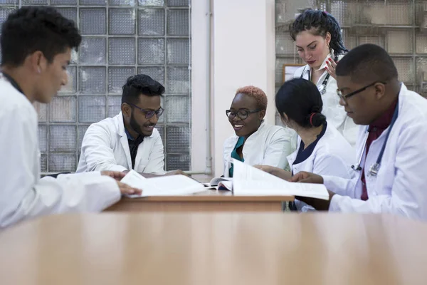 Медична консультація. Група молодих чоловіків змішаної раси, сидячи за столом у лікарняному кабінеті, обговорює медичні теми . — стокове фото