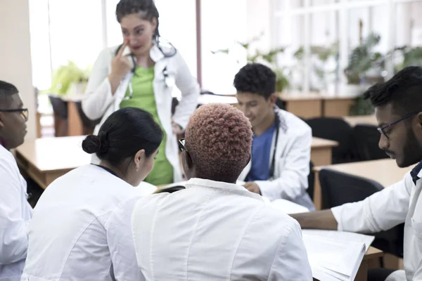 Лікарі на медичній конференції. Група молодих людей змішаної раси, сидячи за столом, слухаючи лектора . — стокове фото