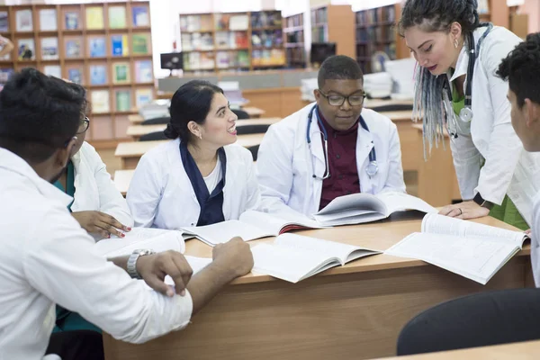 Лікар медицини. Група молодих людей змішаної раси, сидячи за столом в кабінеті лікарні, читала медичну літературу — стокове фото