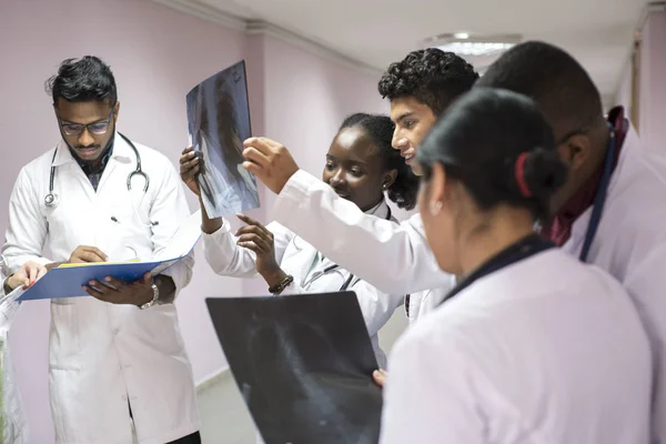 Raza mixta, jóvenes doctores. En el pasillo del hospital tiene una radiografía en sus manos, la examina . — Foto de Stock