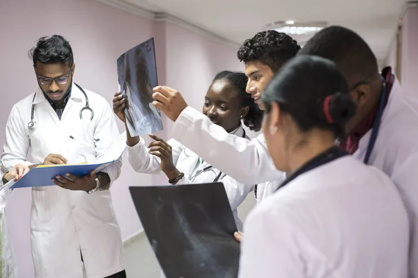 Mixed race, young doctors. In the corridor of the hospital holds an x-ray in his hands, examines it. — 스톡 사진