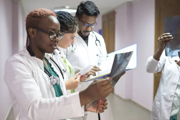 Група молодих лікарів змішаної раси різної статі. Перебуваючи в лікарні, дивлячись на рентген — стокове фото