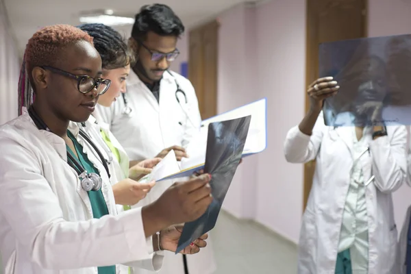 Група молодих лікарів змішаної раси різної статі. Перебуваючи в лікарні, дивлячись на рентген — стокове фото