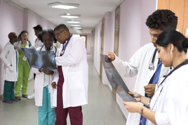 A group of young doctors, mixed race. In the corridor of the hospital, doctors look at X-rays, solving medical problems. — 스톡 사진
