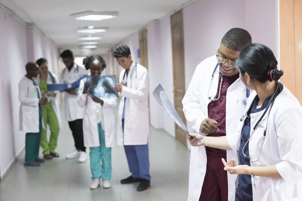 A group of young doctors, mixed race. In the corridor of the hospital discussing medicine, looking at the x-ray — Stock Photo, Image