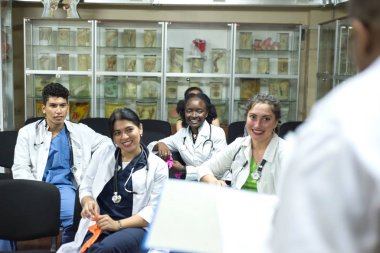 Tıp öğretmeni, tıp öğrencileri için bir ders veriyor. Farklı cinsiyetlerden, farklı ırklardan bir grup genç sınıftaki sandalyelere oturur.