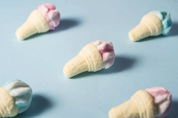 Caramelos de malvavisco, en forma de pequeños conos de helado de color azul y rosa, sobre un fondo azul. Sombras pasteles. Concepto de verano mínimo —  Fotos de Stock