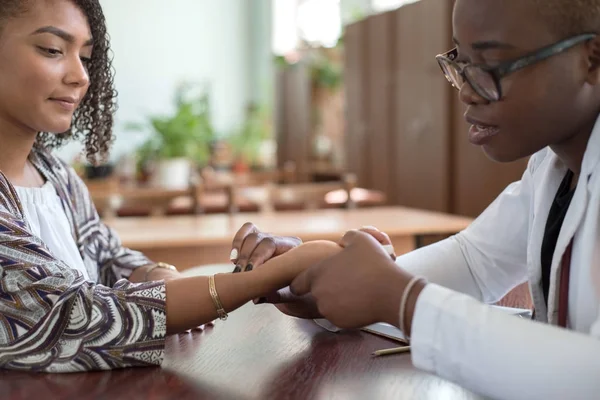 African girl doctor measures the pulse of a Hispanic patient. Blood pressure. Mixed race doctor and patient — 스톡 사진