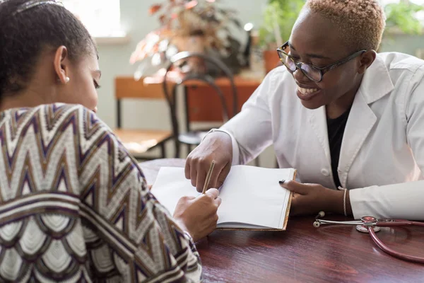 Hispanic patient signs treatment agreement with African female doctor. Young people of mixed race. The trust of the patient and the doctor. Voluntary Informed Consent — 스톡 사진