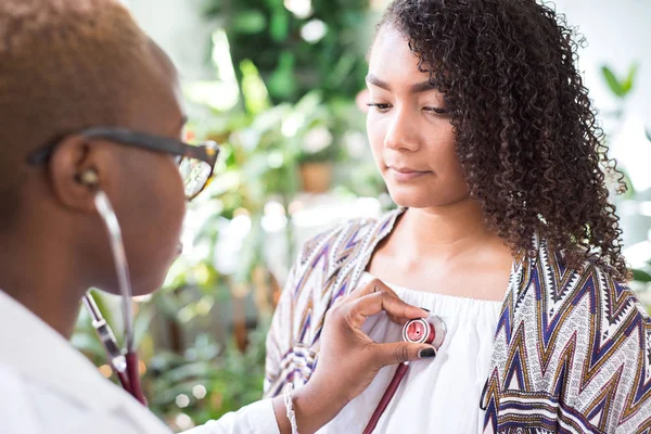 African American girl doctor using a stethoscope to conduct auscultation for a patient. Mixed Race Youth — 스톡 사진