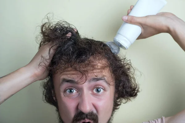 Ritratto di un ragazzo giovane, con i capelli sovrappeso, i capelli lunghi. Versare lo shampoo — Foto Stock
