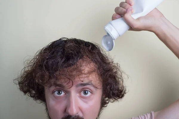 Ritratto di un ragazzo giovane, con i capelli sovrappeso, i capelli lunghi. Versare lo shampoo — Foto Stock