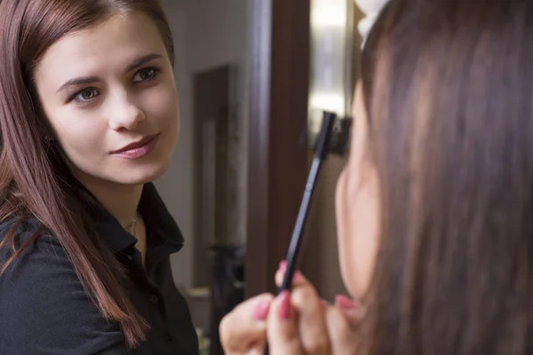 Porträtt av en ung vacker makeup artist flicka. Makeup mästare gör makeup till en flicka. — Stockfoto