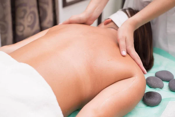 Una joven disfruta de los tratamientos de spa. Manos de un masajista terapeuta, esteticista hacer masajes . — Foto de Stock