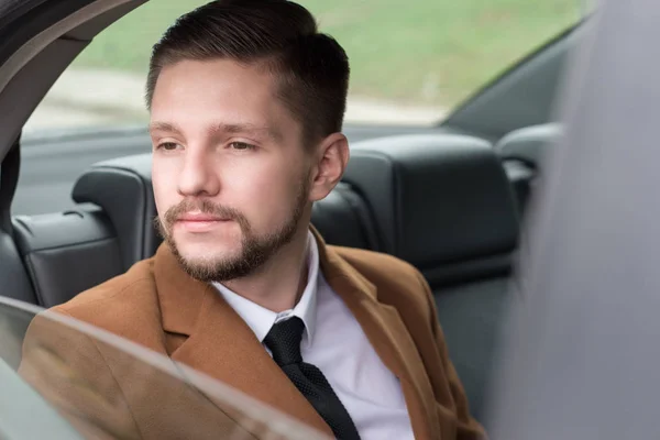 Retrato de un joven con barba. Empresario en un coche en el asiento del pasajero paseos a la oficina, para trabajar —  Fotos de Stock