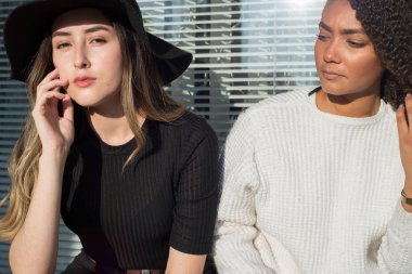 Bir dükkanın arka planında oturan iki güzel İspanyol kızın portresi. İçlerinden biri şapka takıyor. Moda fotoğrafı.