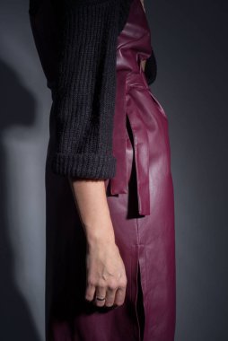 Kaliteli deri bir elbise ve siyah bir süveter giymiş kırmızı saçlı genç bir kızın reklam fotoğrafları kataloğu. Koyu gri bir arka planda. Biçim ve moda.