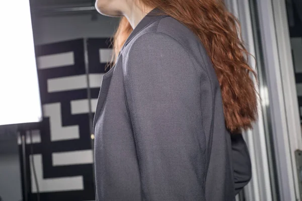 Retrato de una hermosa mujer pelirroja de treinta y siete años, en una tienda de ropa de mujer, una chica probándose una chaqueta de cuero hecha de tela de alta calidad junto al espejo . — Foto de Stock