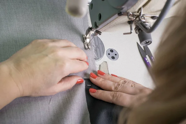 Zbliżenie rąk szwaczki szyjącej odzież, szyjącej tkaninę za maszyną do szycia — Zdjęcie stockowe