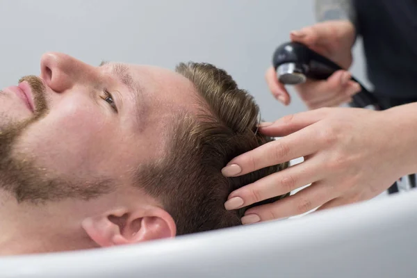 Närbild av en man hårvård mästare tvätta en mans huvud i ett handfat efter att ha klippt håret — Stockfoto