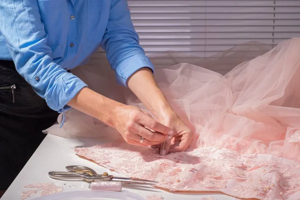 Projektant couturier, w jego studio produkcji odzieży. Ręcznie robiona odzież, profesjonalne szycia dekoracyjne kwiaty na różowej sukience — Zdjęcie stockowe