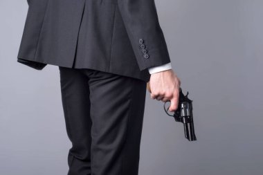 İş elbisesi giymiş silahlı bir adamın portresi. Gri bir arkaplanda.