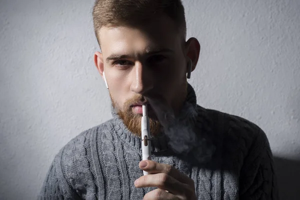 클로즈업. 수염을 기른 젊은 남자가 현대 첨단 전자 담배인 이코스를 피우는 모습 — 스톡 사진