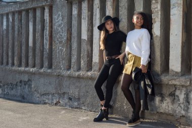 İki güzel İspanyol kızın genel planı, Y nesli, eski doku duvarında duruyor, gülümsüyorlar.