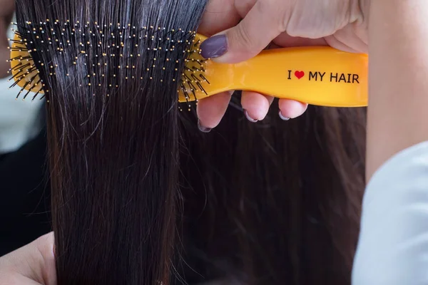 Primer plano de un peluquero peinándose el pelo con un peine amarillo con el nombre Me encanta mi cabello . — Foto de Stock