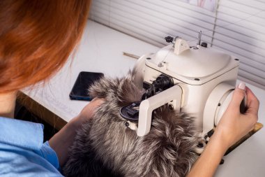 Kürkten giysi imalatında uzman. Dikiş makinesindeki kadın tasarımcı. Kürk giysi dikme süreci