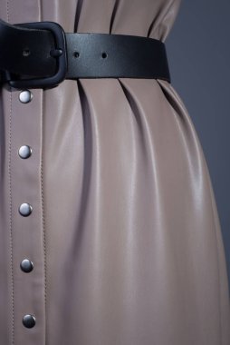 ... bej rengi deri bir elbise ve siyah bir kazak giyen kızıl saçlı genç bir kızın katalog reklam fotoğrafı. Koyu gri bir arkaplanda