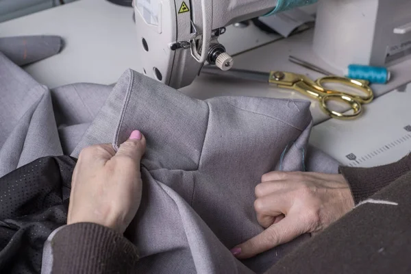 Мастер кутюрье, на фоне швейной машинки, шьет одежду из высококачественной ткани, ручной работы мастера-профессионала в производстве одежды — стоковое фото