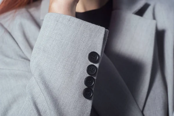 closeup of a sleeve with buttons of a gray female jacket, business girl