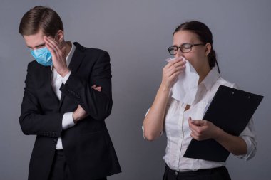 İş elbiseli iki genç iş adamının portresi. Maskeli adam hasta bir kızın enfeksiyonundan korkarak yüzünü eliyle kapatıyor. Mendile hapşıran..
