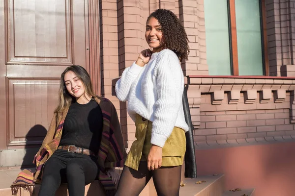 Ein paar schöne junge modische spanische Mädchen, vor dem Hintergrund eines Backsteingebäudes. posiert für die Kamera. Generation z — Stockfoto