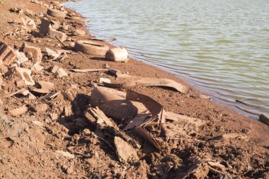 Atık tarafından kirletilmiş, nehir kıyısındaki makine lastikleri.
