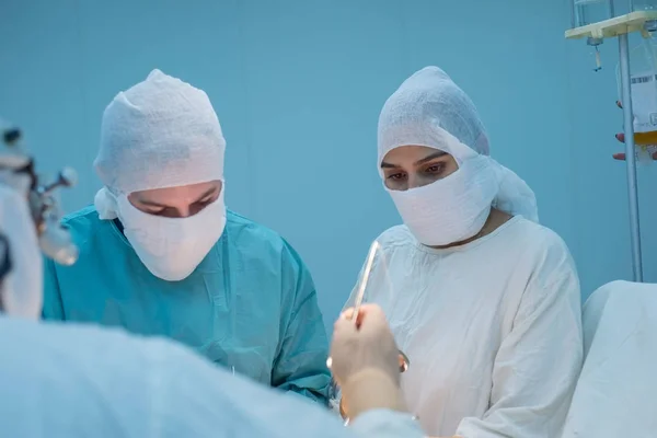 Squadra operativa. Una chirurga che guarda la telecamera durante un'operazione. Condizioni per una sala operatoria sterile. Intervento chirurgico — Foto Stock